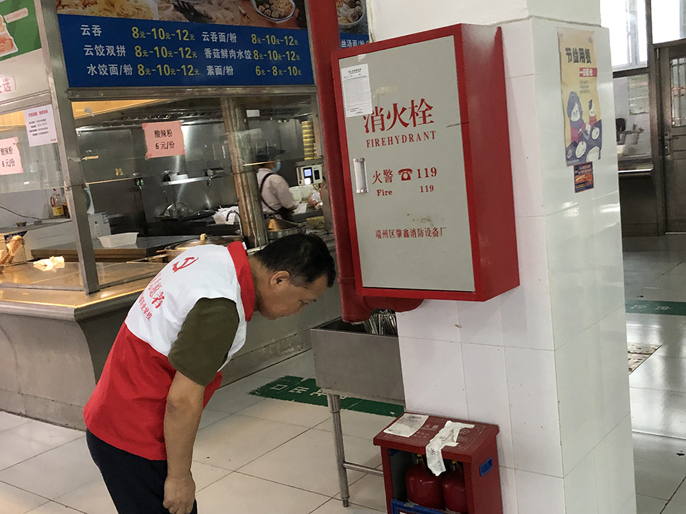 照片2：学校党总支书记、副校长沈小明带领党员志愿者查看学校消防设备